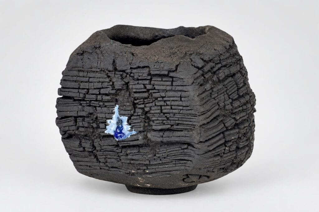Vase en céramique noire avec texture stratifiée unique.