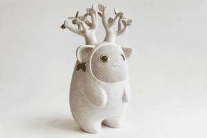 Figurine en céramique d'un animal mignon avec arbre en fleurs sur la tête.