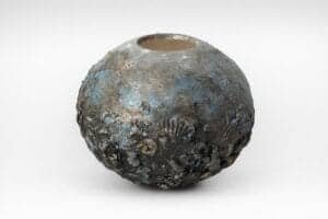 Vase rond en céramique avec texture rugueuse et finition émaillée.