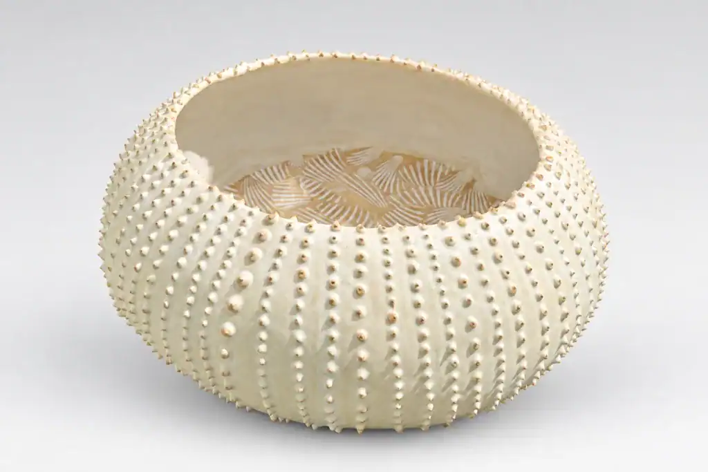 Vase rond en céramique blanche avec texture en relief.